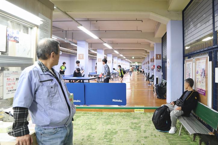 <font size ='-1' color=blue>A receptionist of ”Metro Table tennis”, Mr. Sera watching over people practicing.</font>